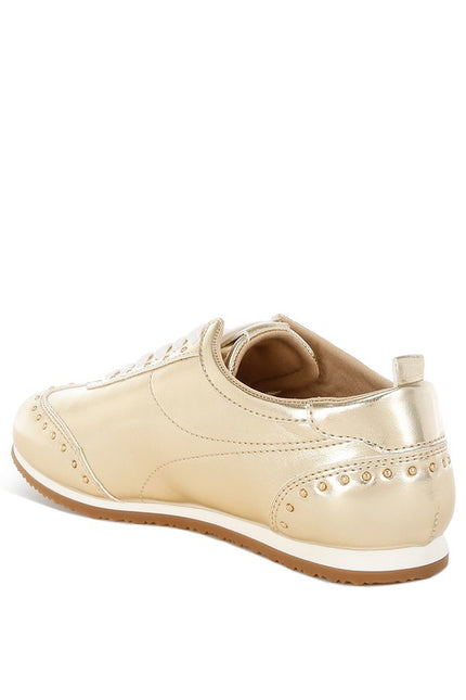 Side view of gold faux leather sneakers with studded design