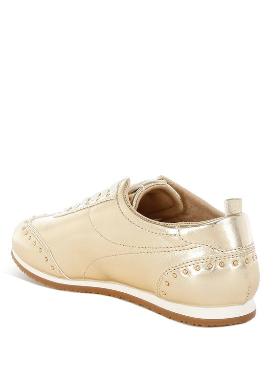 Side view of gold faux leather sneakers with studded design